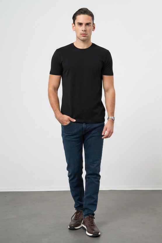 Man wearing a black t-shirt and blue jeans standing against a plain white background
